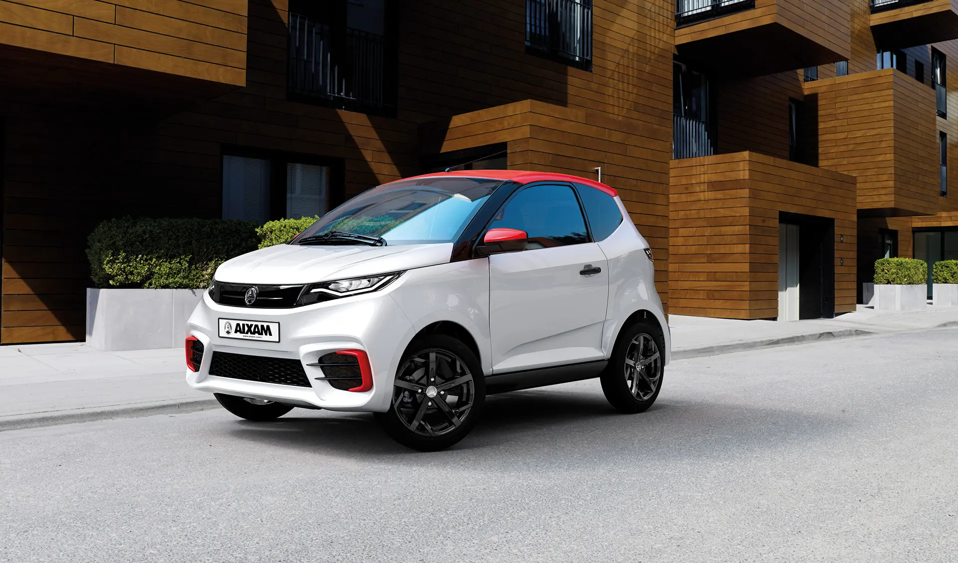 Vue d'une voiture sans permis Aixam, modèle City sport blanc toit rouge devant un immeuble.